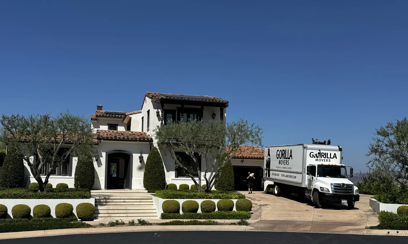 Gorilla Movers truck backed into the driveway of a 4S Ranch home while a mover carries a wrapped piece in through the garage