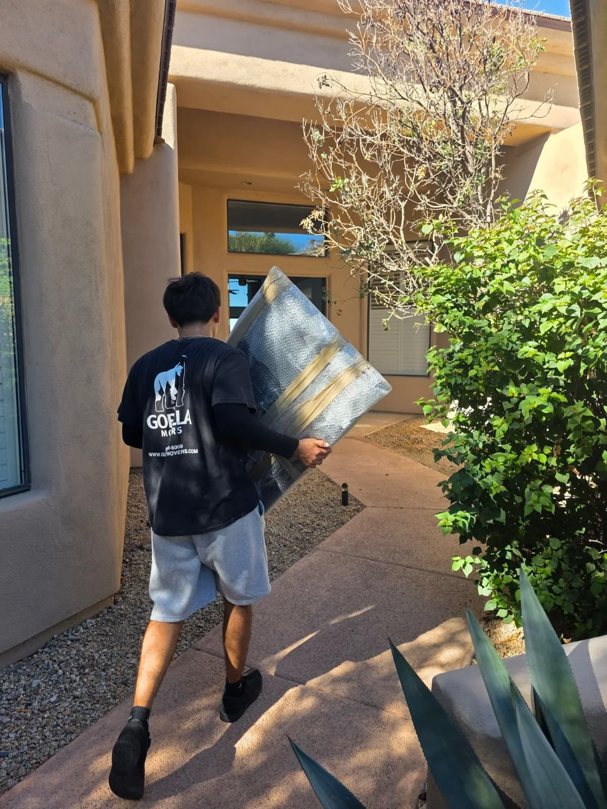 Gorilla Movers crew member carrying a bubble-wrapped mirror into an Arizona home