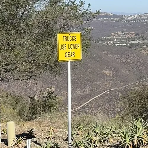 A TRUCKS USE LOWER GEAR road sign on an interior Cielo street, with the valley floor far below