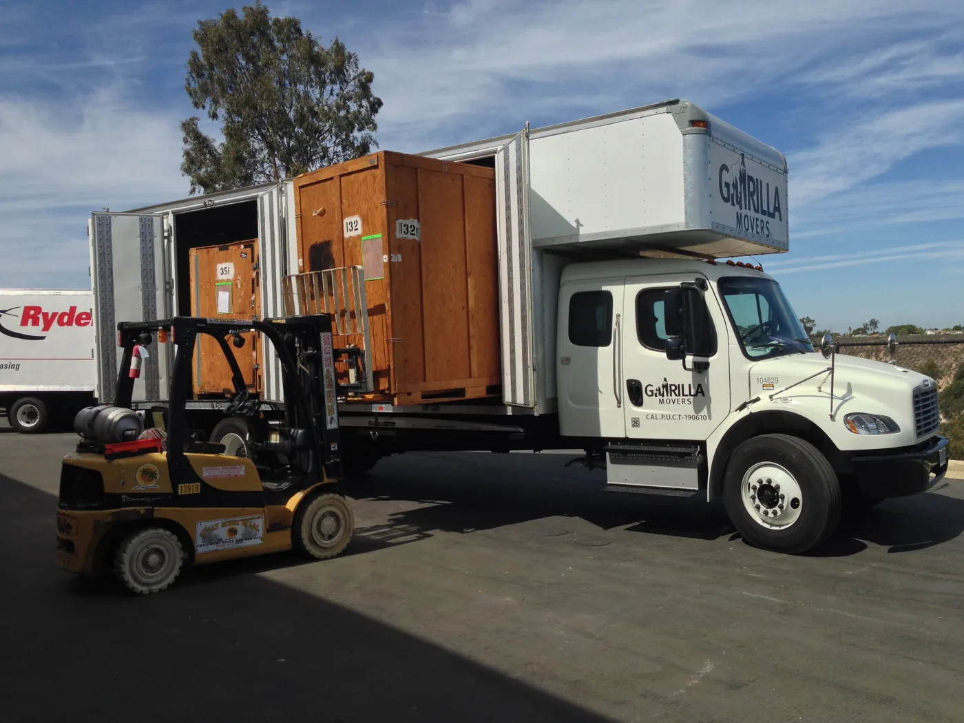 Forklift loading a wooden crate onto a Gorilla Movers truck