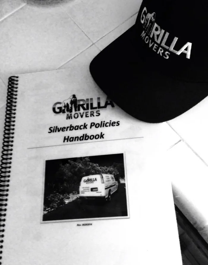 The Gorilla Movers Silverback Policies Handbook and a company cap, the written standards every crew is trained to