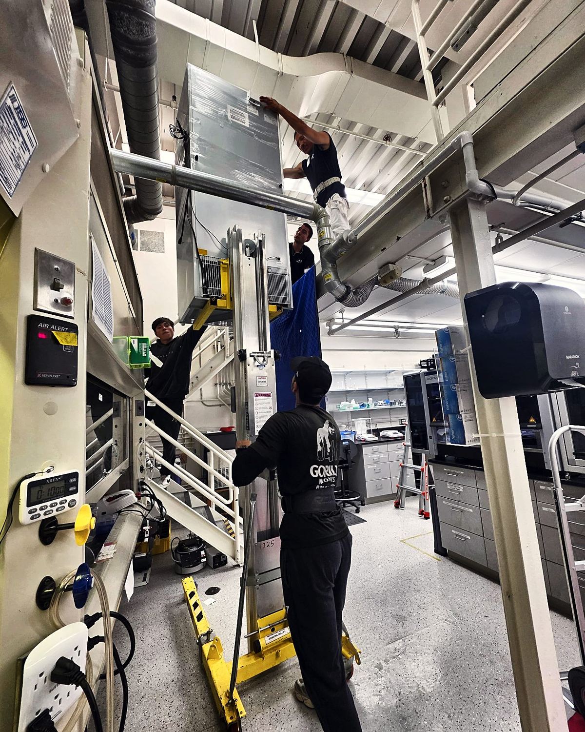 Crew rigging a fume hood on a Genie lift during a San Diego biotech lab move