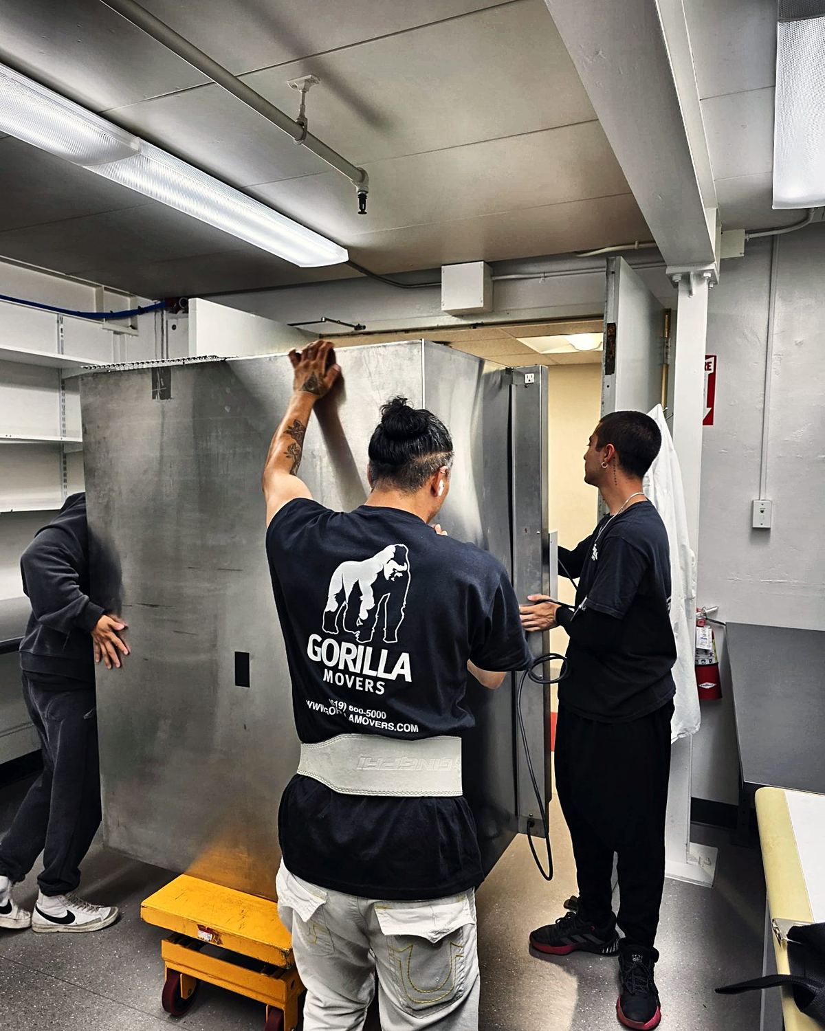 Crew threading heavy lab equipment through a tight doorway