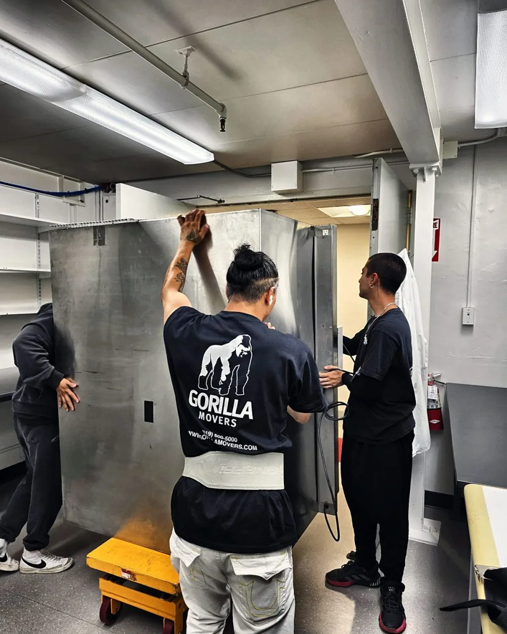 Crew navigating heavy medical lab equipment through a tight doorway