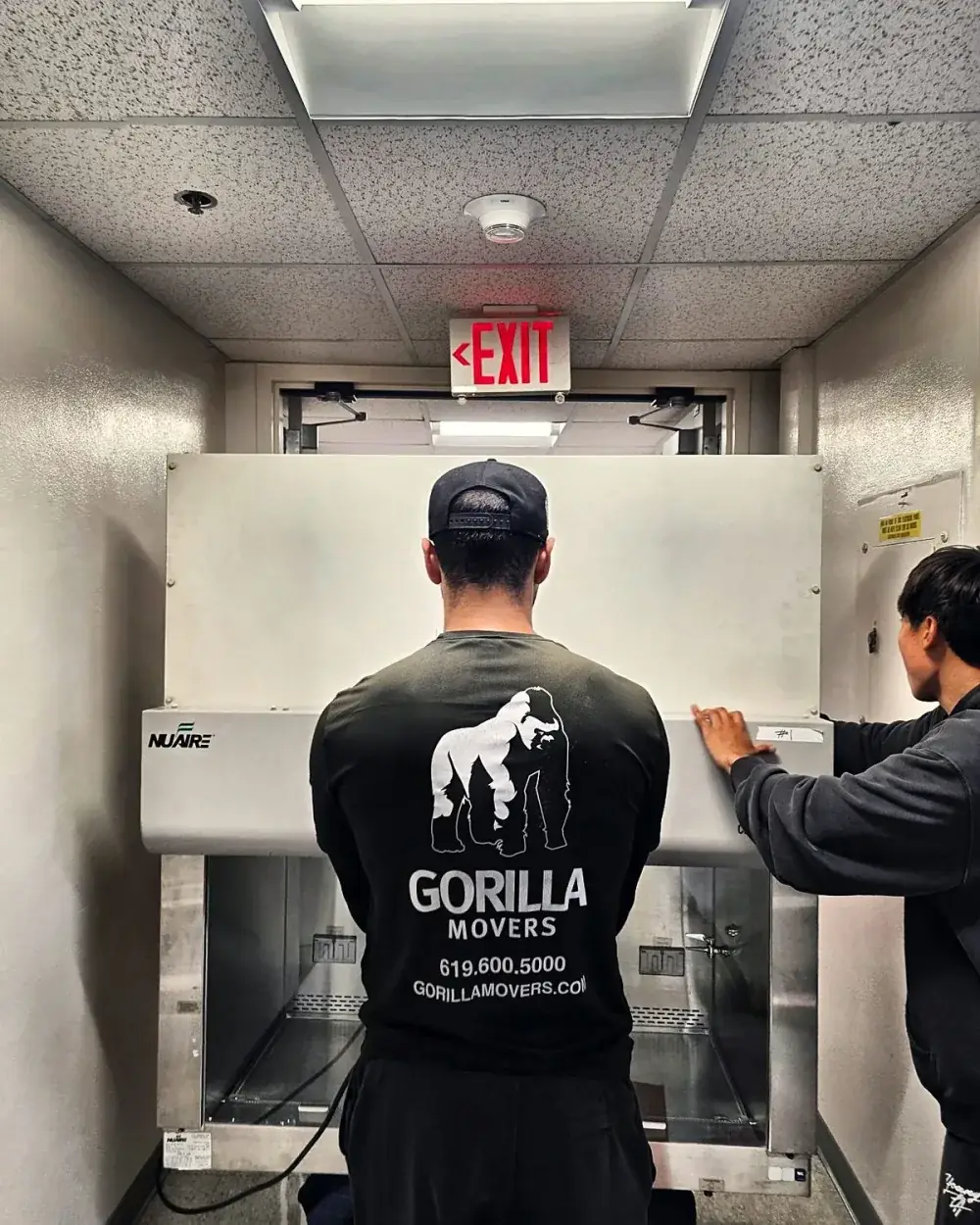 Movers handling a NuAire biosafety cabinet in a San Diego medical laboratory