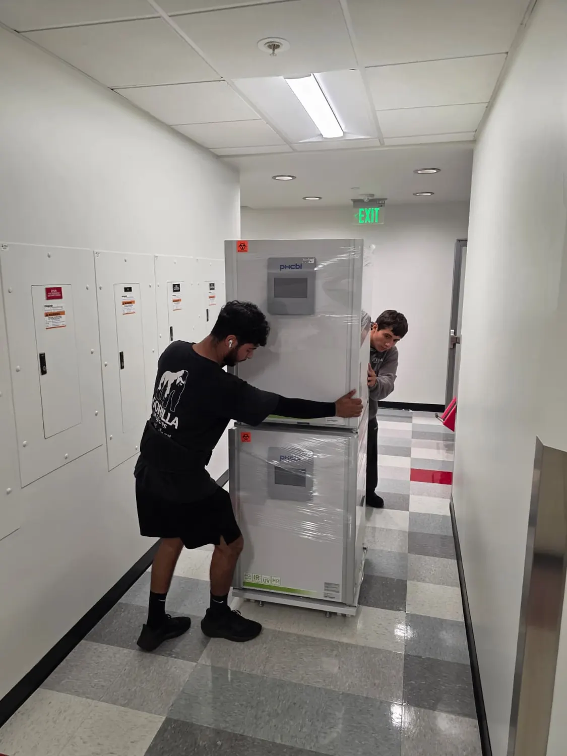 Gorilla Movers crew guiding shrink-wrapped stacked CO2 incubators through a lab hallway in San Diego