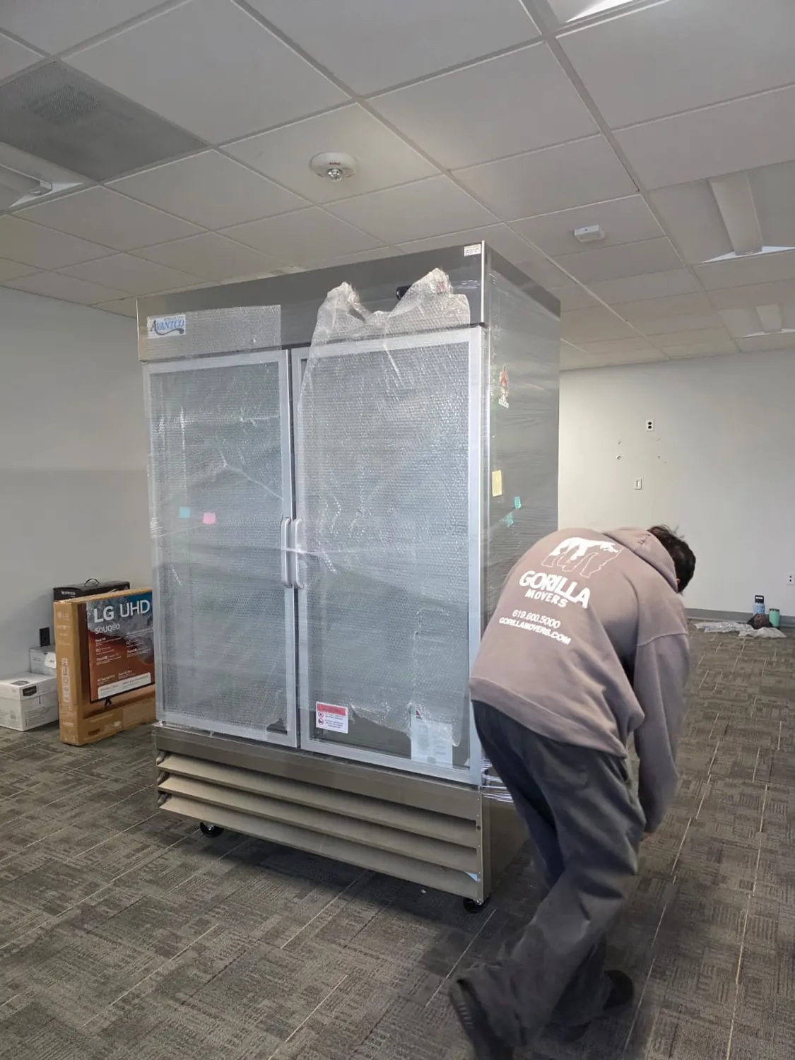 Double-door lab refrigerator bubble-wrapped and shrink-wrapped for a cold-chain lab move in San Diego