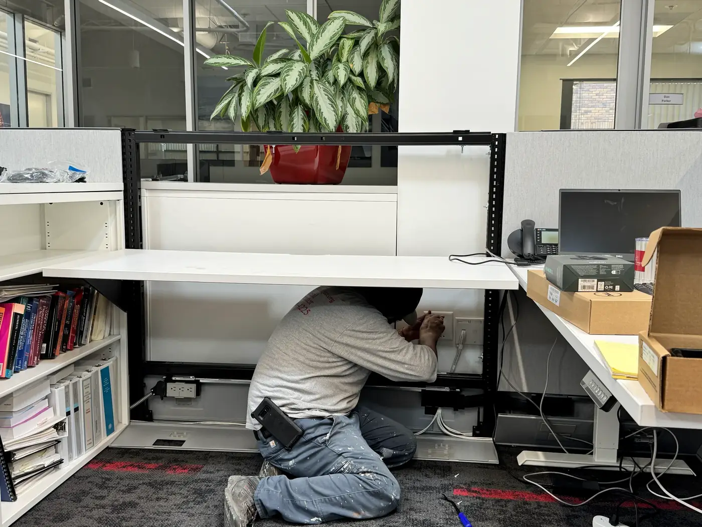 Gorilla Movers installer wiring workstation power during an FF&E install in a San Diego office