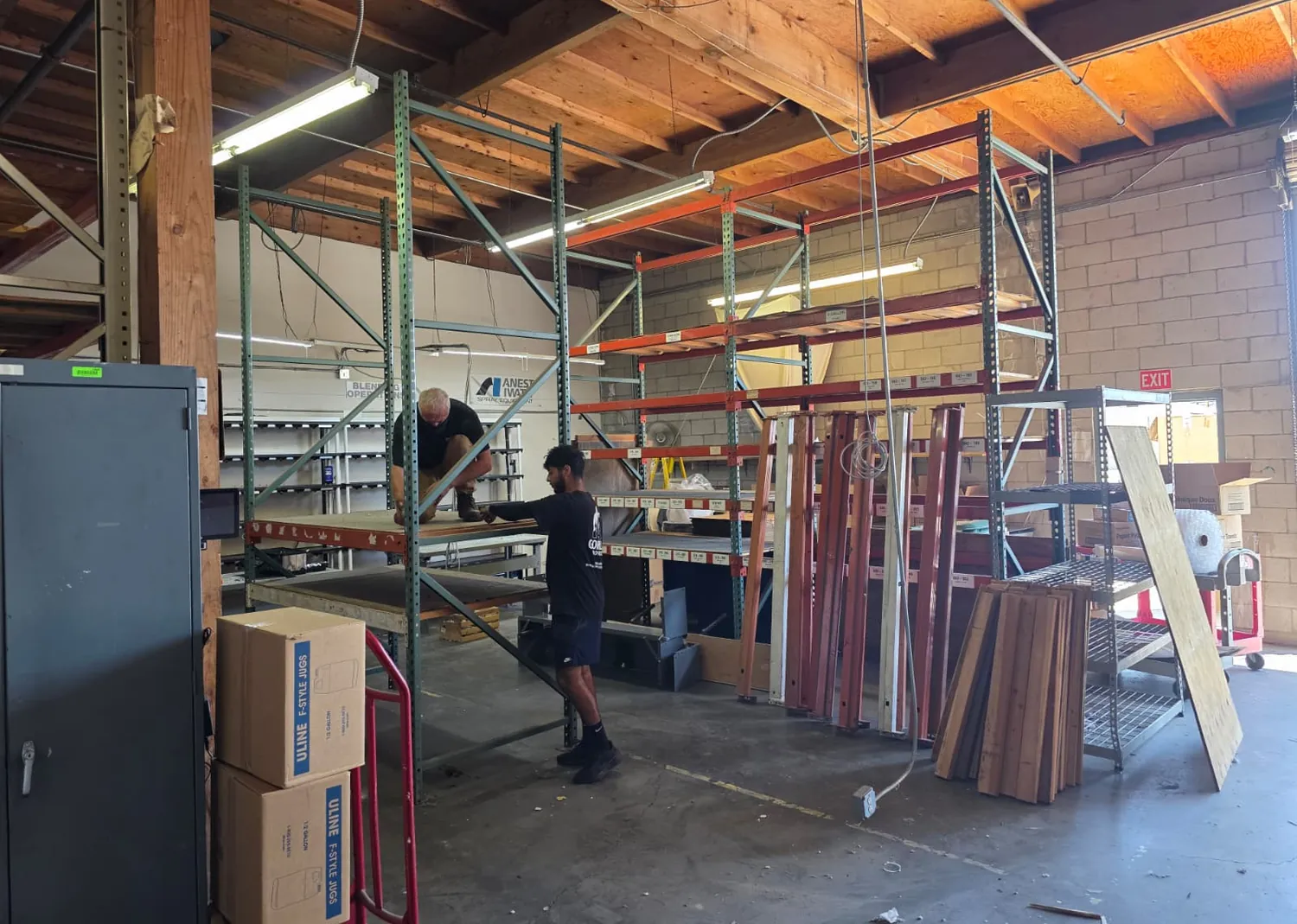 Two Gorilla Movers crew members assembling pallet rack uprights and beams in a warehouse