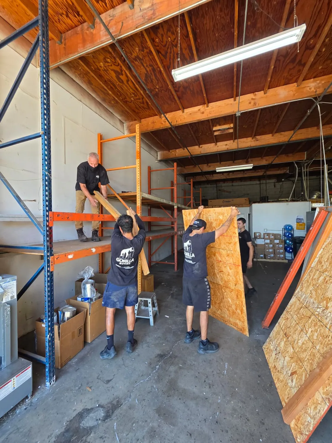 Gorilla Movers crew installing plywood decking on pallet racking in a San Diego warehouse