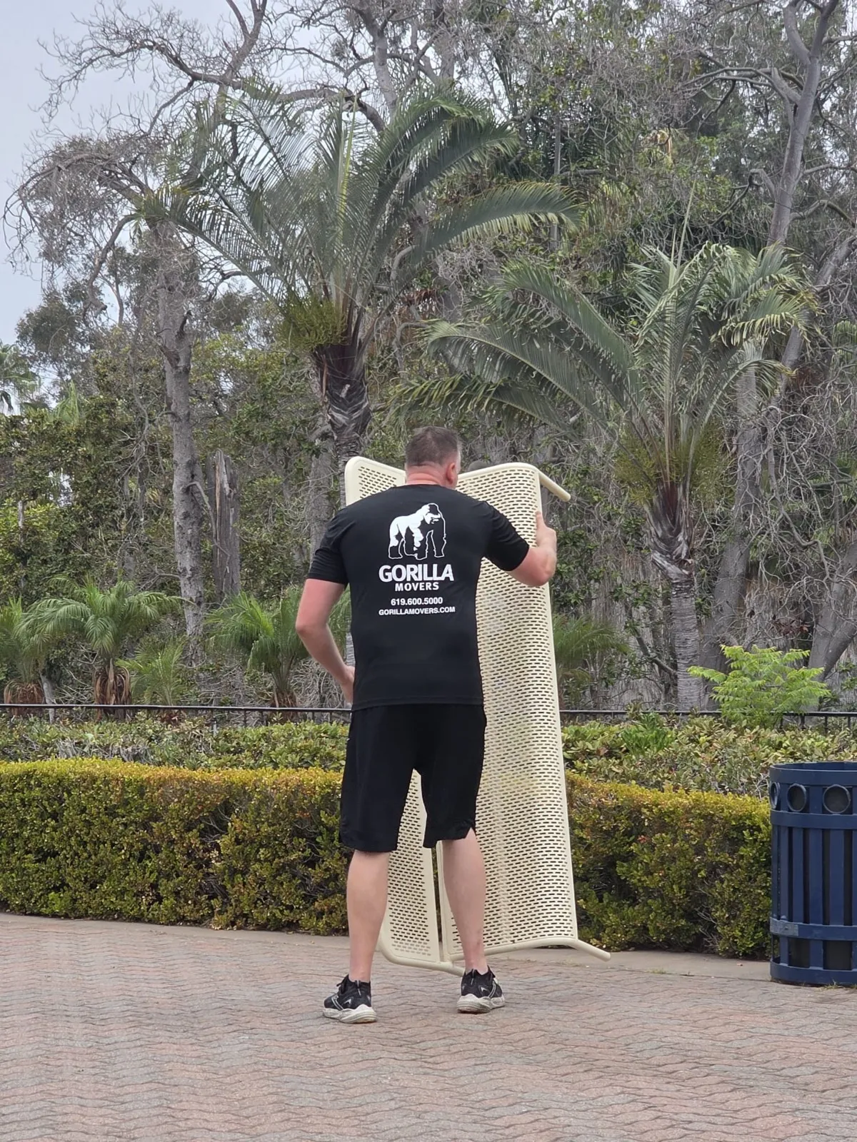 Gorilla Movers mover carrying a 70-pound bench past the Spreckels Organ Pavilion in Balboa Park