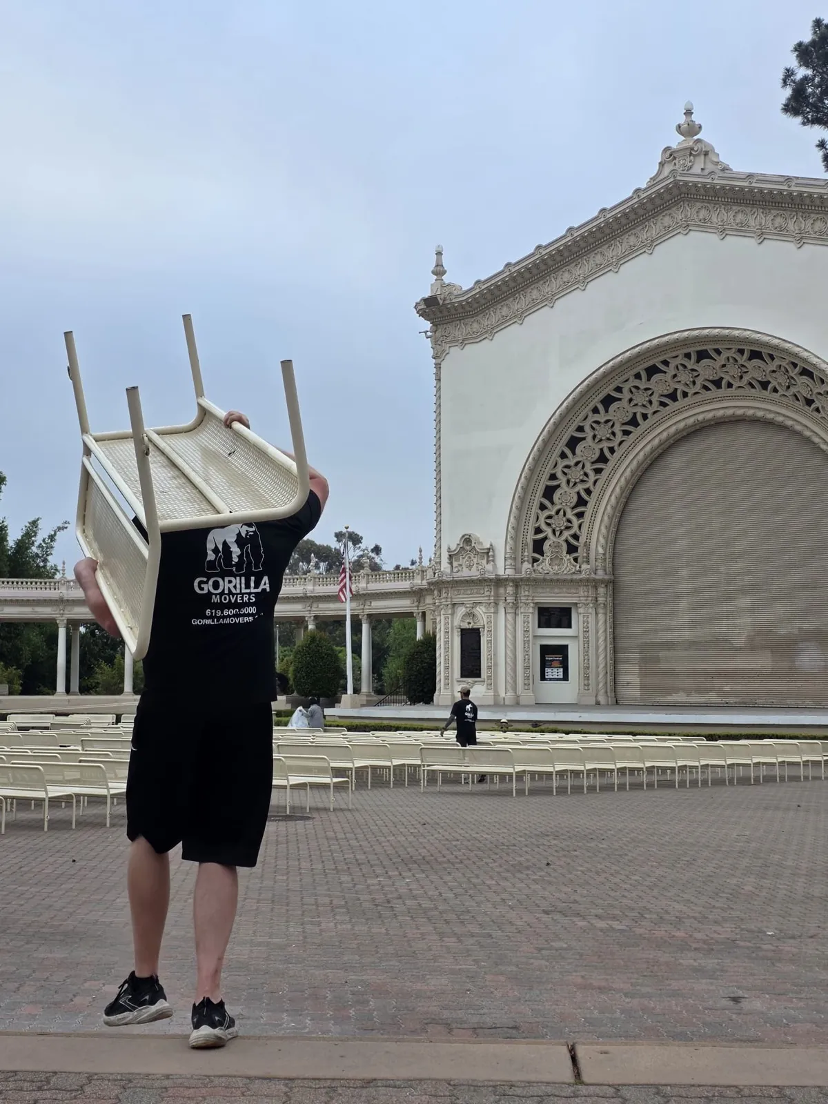 Gorilla Movers crew member carrying a bench along the Balboa Park colonnade